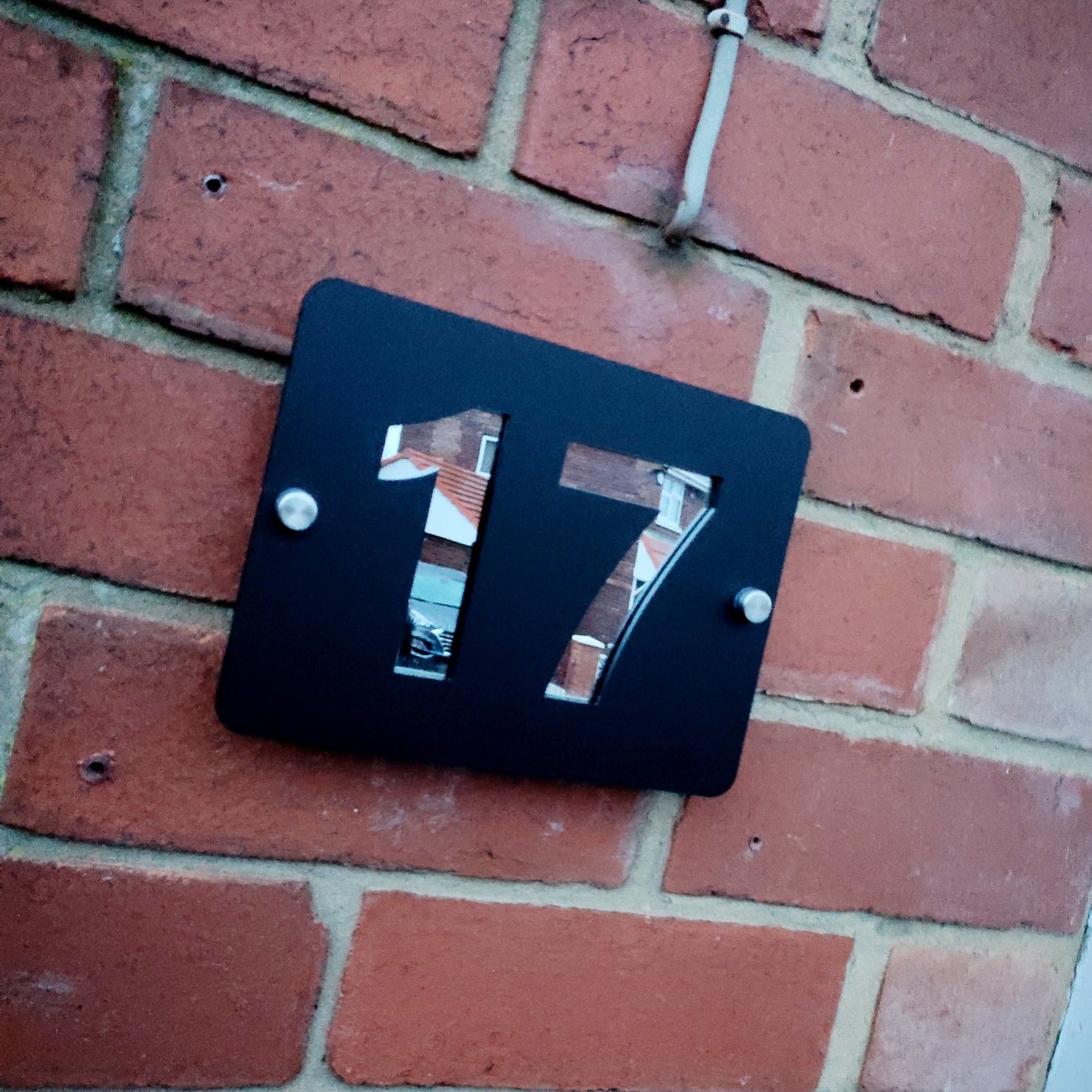 Black metal door number 17 plaque on red brick wall
