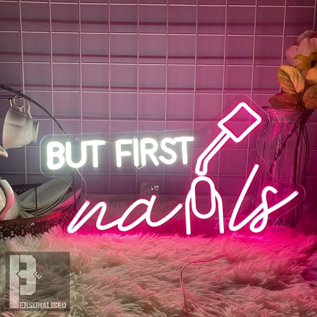 Pink neon But First Nails sign with polish bottle on tiled wall