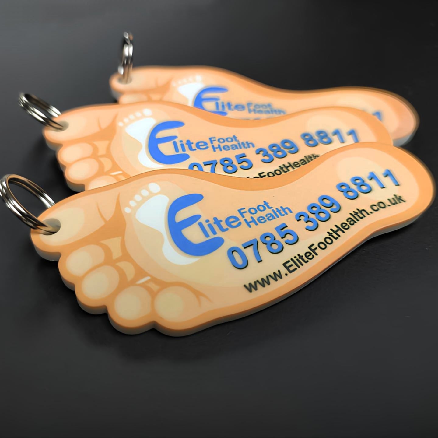 Orange foot-shaped keychains with elite foot health branding