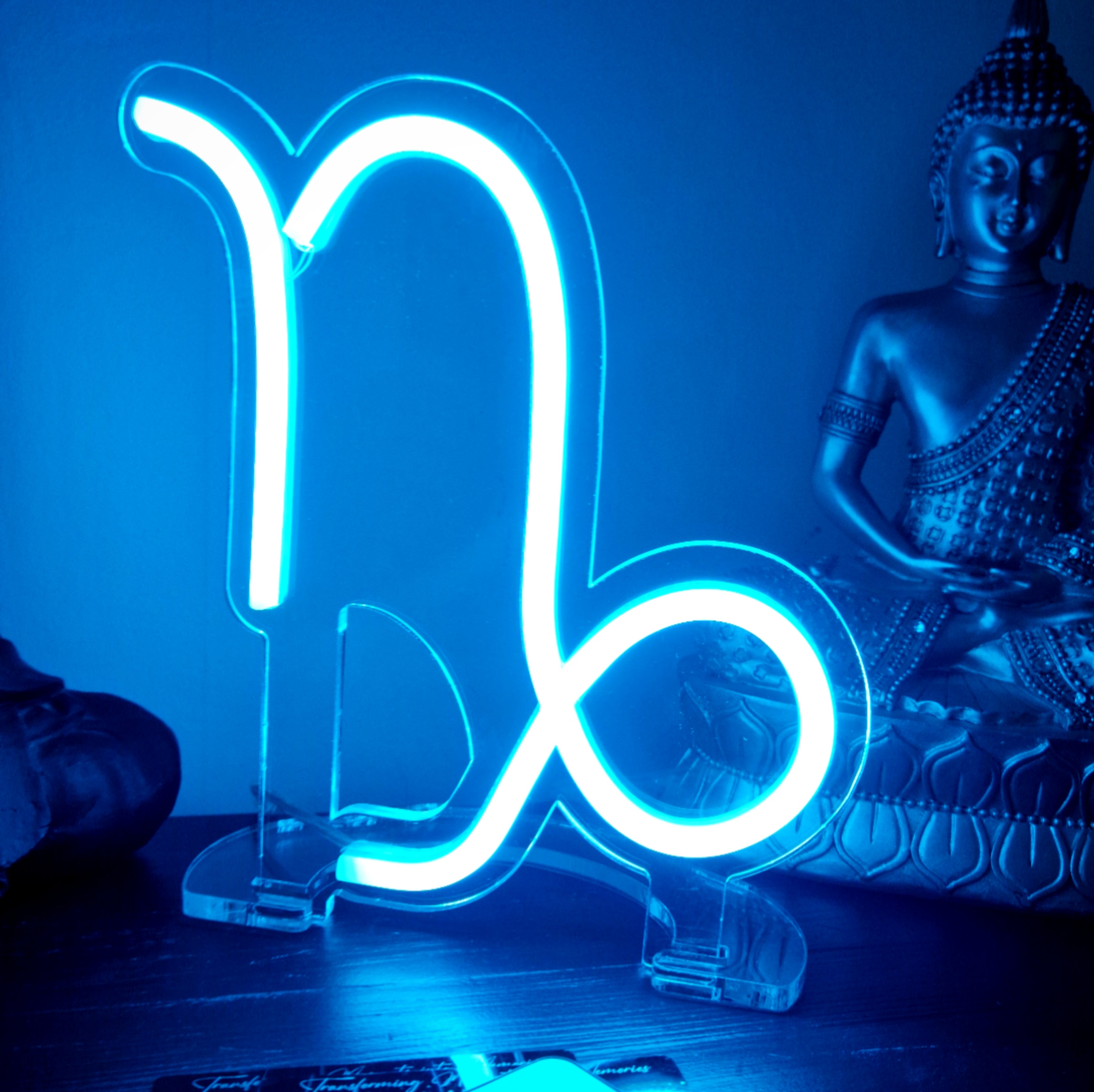 Glowing blue Capricorn zodiac neon sign on clear acrylic stand