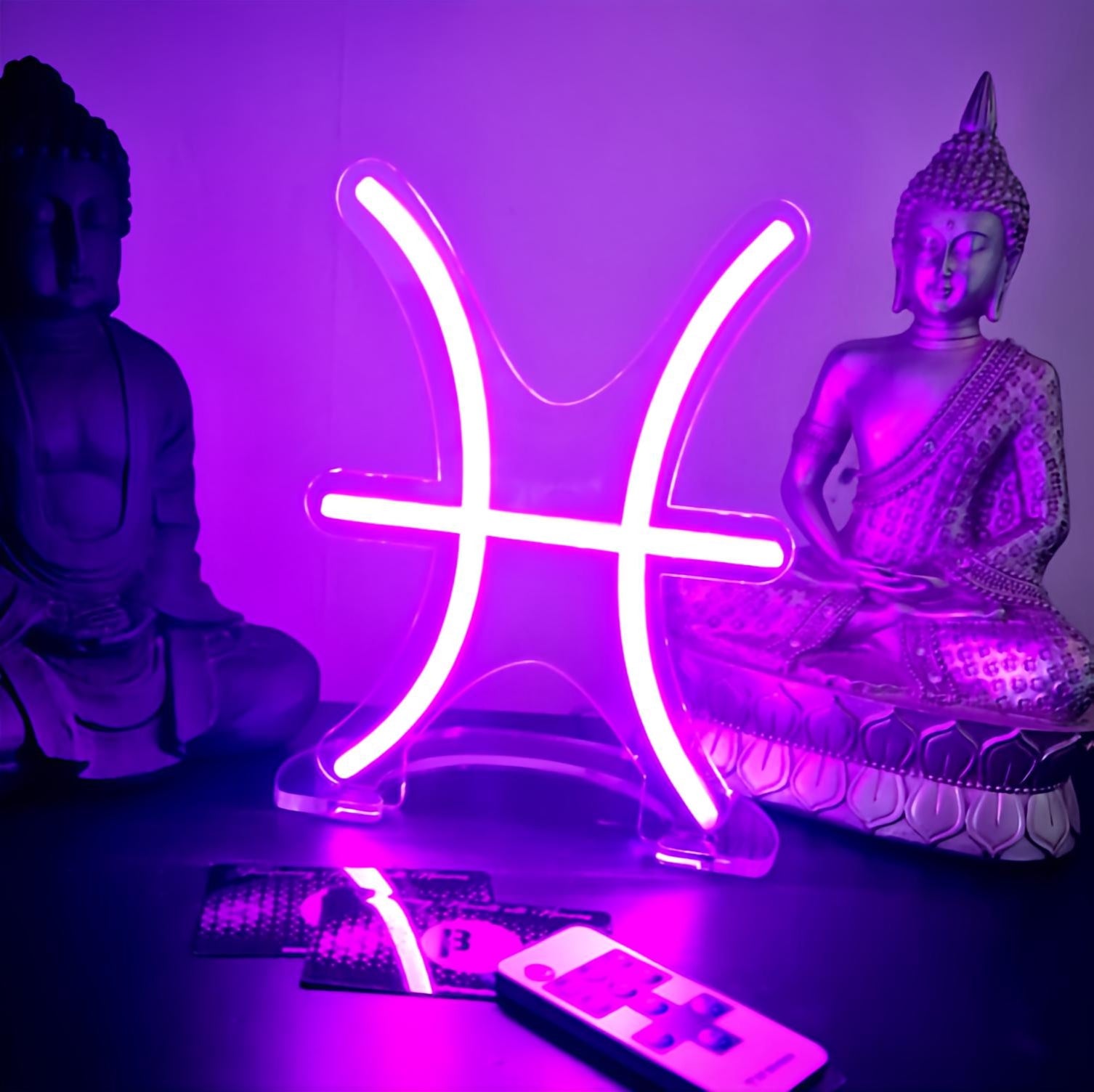 A neon zodiac star sign representing the Pisces sign, with a purple glow, placed on a table alongside a small figure and a remote control.
